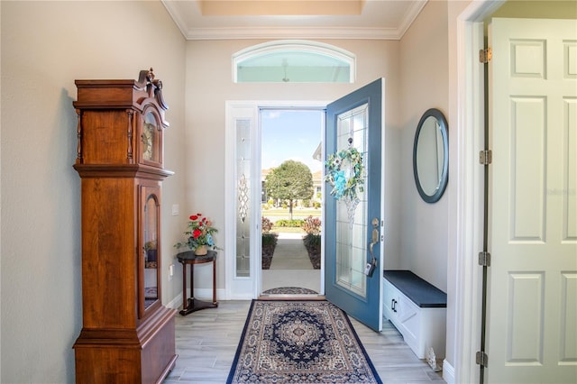 entrance foyer with light wood-type flooring, baseboards, and crown molding