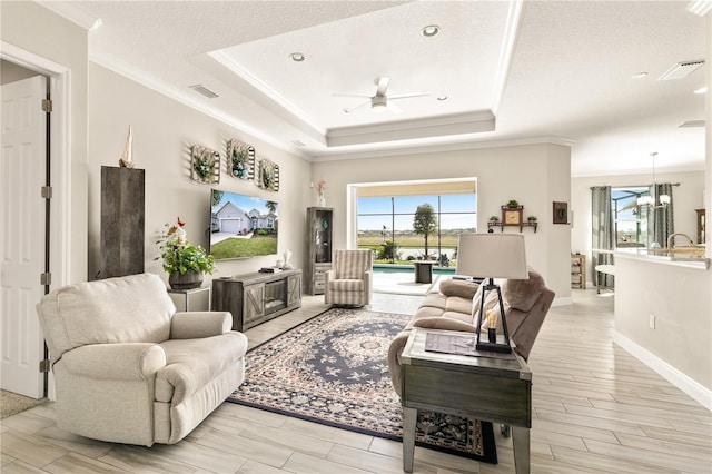 living area featuring a tray ceiling, plenty of natural light, and visible vents