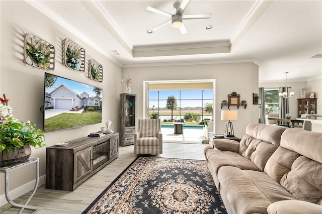 living area featuring crown molding, a tray ceiling, ceiling fan with notable chandelier, light wood-style flooring, and a textured ceiling