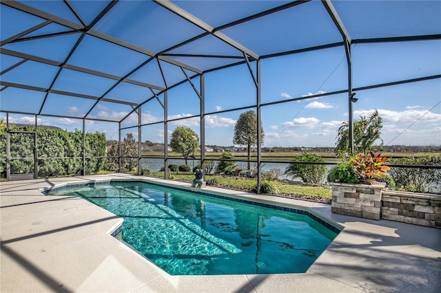 outdoor pool featuring glass enclosure, a patio, and a water view