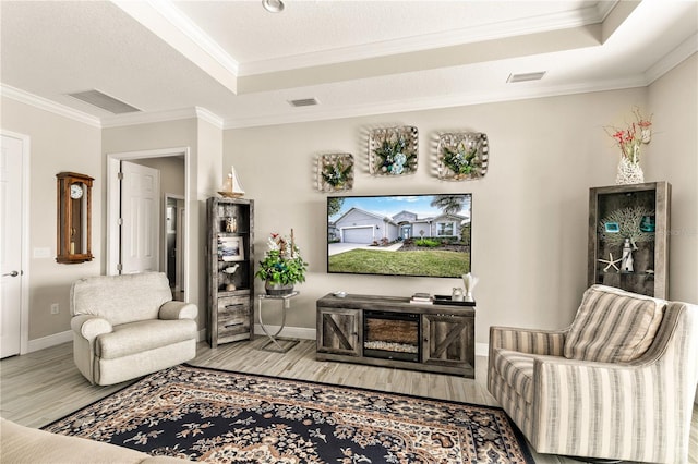 living area with visible vents, a tray ceiling, and ornamental molding