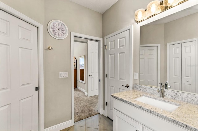 bathroom featuring tile patterned floors, a closet, baseboards, and vanity