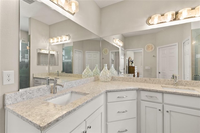 full bathroom with a shower stall, double vanity, visible vents, and a sink