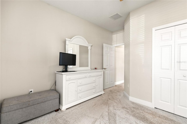 bedroom with visible vents, light carpet, baseboards, and a closet