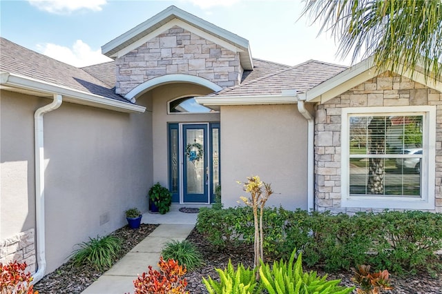 doorway to property with a shingled roof, crawl space, stone siding, and stucco siding