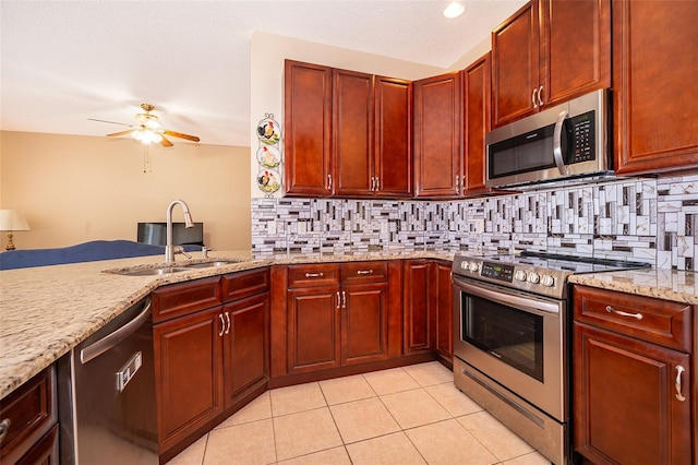 kitchen featuring backsplash, dark brown cabinets, light stone countertops, appliances with stainless steel finishes, and a ceiling fan