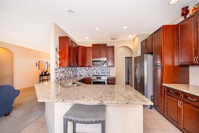 kitchen with arched walkways, backsplash, appliances with stainless steel finishes, and a sink