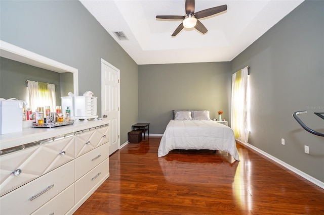 bedroom featuring visible vents, a raised ceiling, baseboards, and wood finished floors