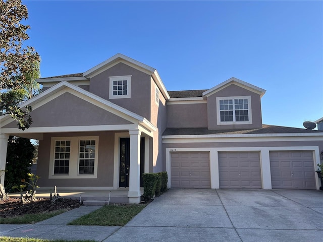 traditional home with concrete driveway, a garage, covered porch, and stucco siding