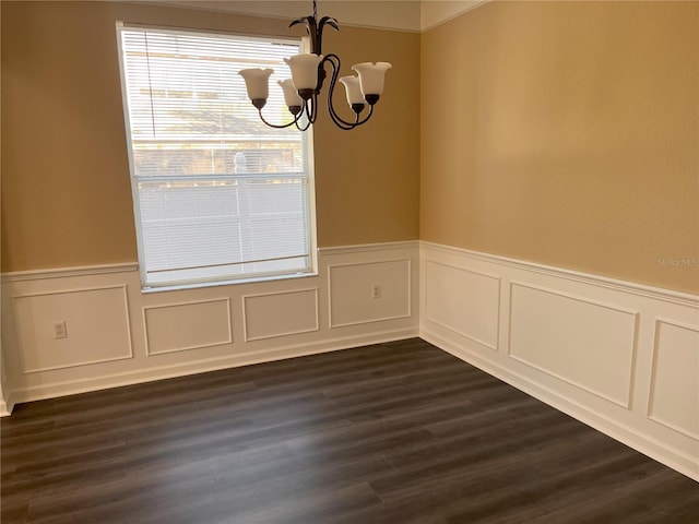 unfurnished dining area with dark wood-type flooring, a notable chandelier, and wainscoting