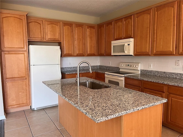 kitchen featuring backsplash, dark stone countertops, light tile patterned flooring, white appliances, and a sink