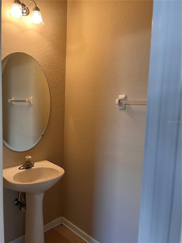 bathroom featuring baseboards and a sink