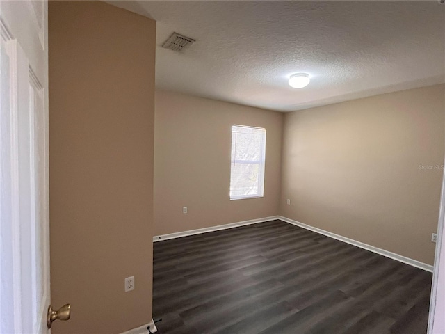 unfurnished room with visible vents, dark wood-type flooring, a textured ceiling, and baseboards