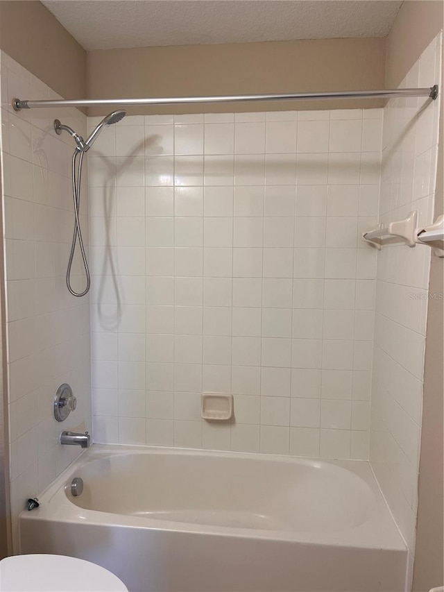full bathroom featuring shower / washtub combination, toilet, and a textured ceiling