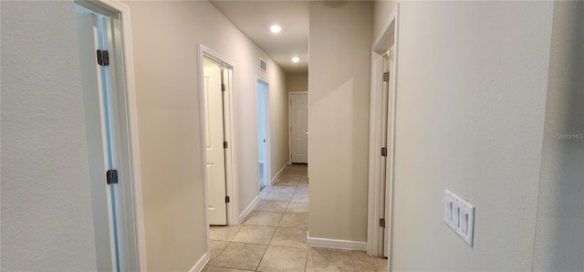 hallway with recessed lighting, light tile patterned floors, visible vents, and baseboards