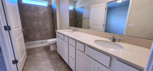 full bathroom featuring double vanity, toilet, tiled shower, and a sink