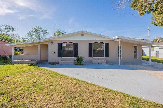 view of front facade with a carport, stucco siding, concrete driveway, and a front yard