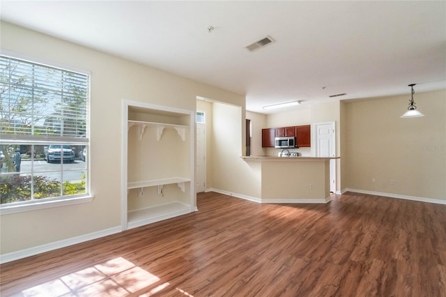 unfurnished living room with visible vents, baseboards, and wood finished floors