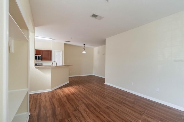 unfurnished living room with dark wood-style floors, visible vents, baseboards, and a sink