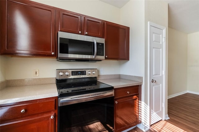 kitchen with appliances with stainless steel finishes, light countertops, baseboards, and wood finished floors