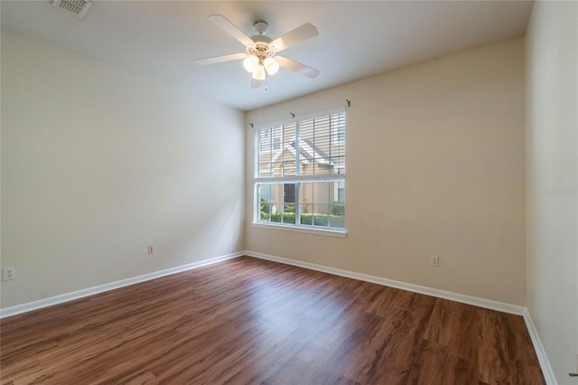 spare room with ceiling fan, visible vents, baseboards, and wood finished floors