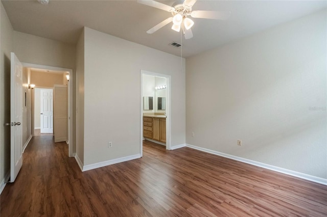 unfurnished bedroom featuring visible vents, ceiling fan, baseboards, wood finished floors, and ensuite bath