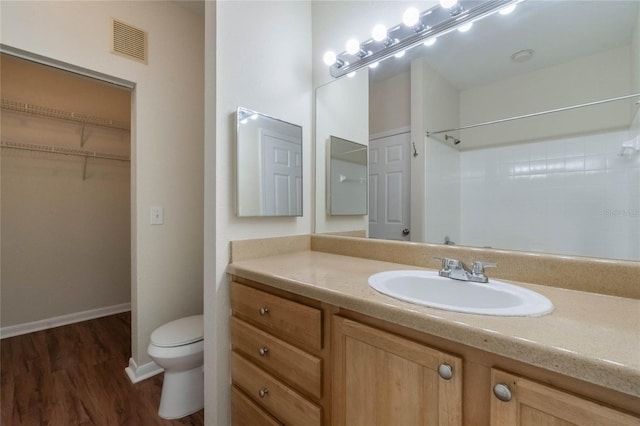 bathroom featuring visible vents, toilet, wood finished floors, baseboards, and vanity