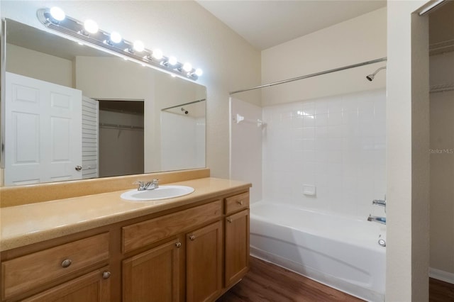 full bathroom with vanity, a spacious closet, wood finished floors, and shower / washtub combination