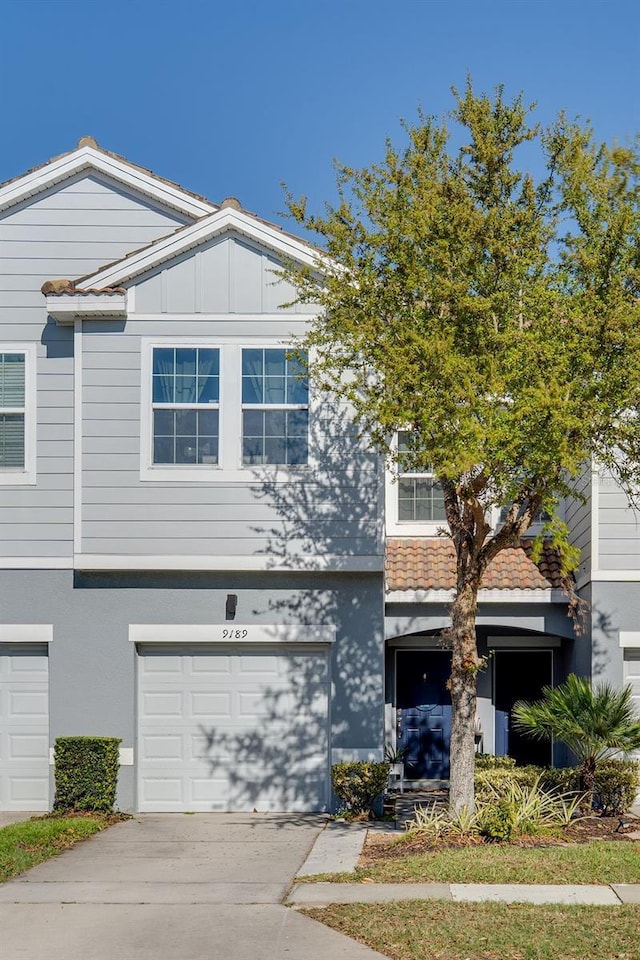 view of property featuring a garage, board and batten siding, driveway, and stucco siding