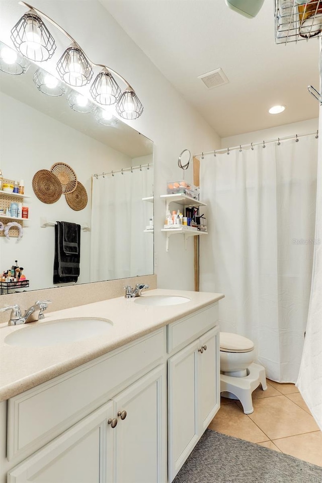 bathroom featuring a sink, toilet, double vanity, and tile patterned floors