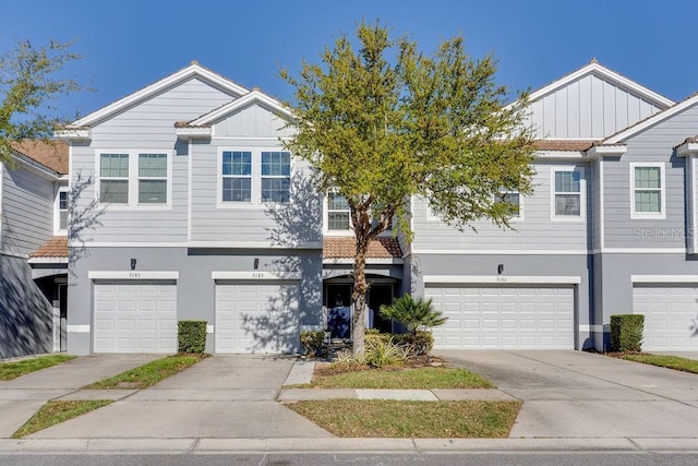 multi unit property featuring stucco siding, a garage, board and batten siding, and concrete driveway