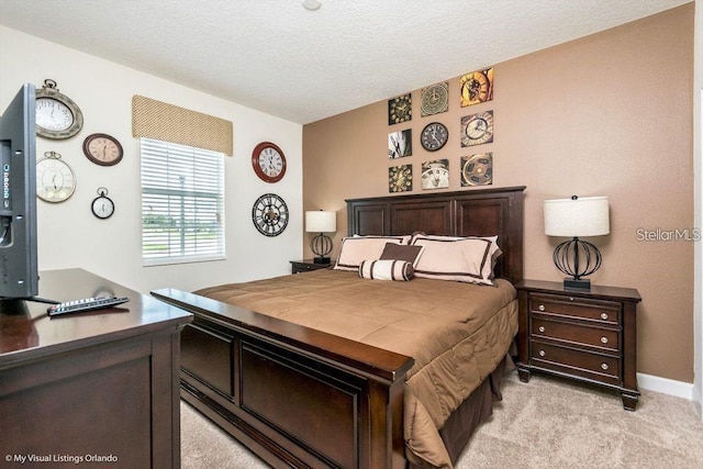 bedroom featuring light carpet, a textured ceiling, and baseboards