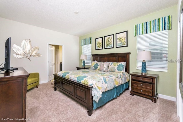 bedroom with baseboards, light colored carpet, and a textured ceiling