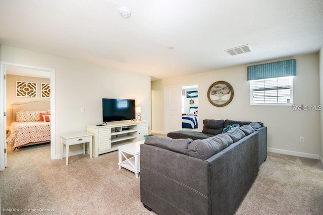 living area with light colored carpet, visible vents, and baseboards