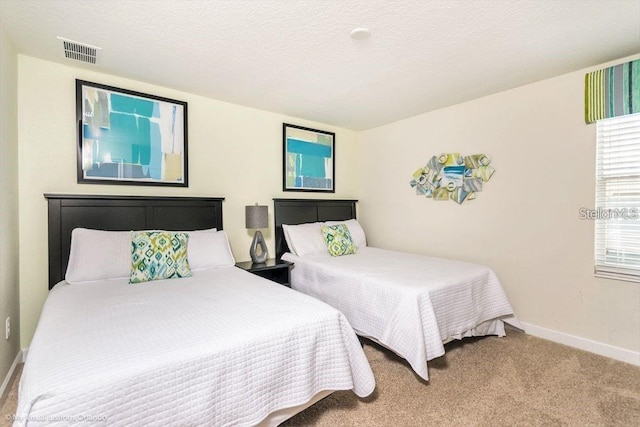 carpeted bedroom featuring baseboards, visible vents, and a textured ceiling