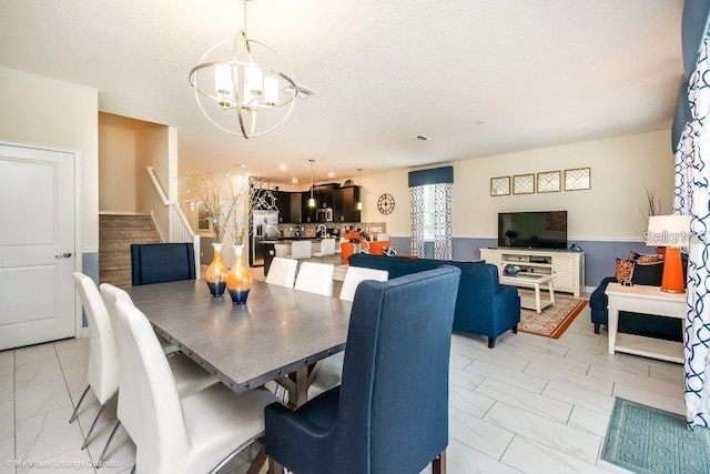 dining area with stairway, a notable chandelier, marble finish floor, and a textured ceiling