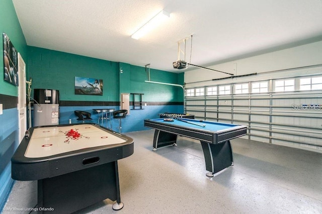 recreation room with billiards, speckled floor, water heater, a garage, and a textured ceiling