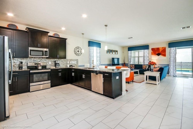 kitchen with light stone countertops, visible vents, open floor plan, appliances with stainless steel finishes, and tasteful backsplash