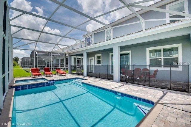 view of pool featuring a lanai, a pool with connected hot tub, and a patio