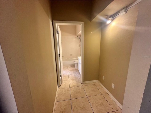 corridor featuring light tile patterned flooring and baseboards