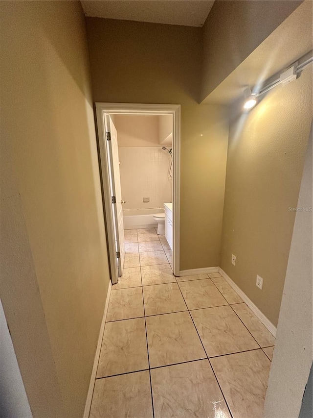 hallway with light tile patterned flooring and baseboards