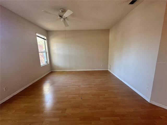 unfurnished room featuring baseboards, a textured ceiling, wood finished floors, and a ceiling fan