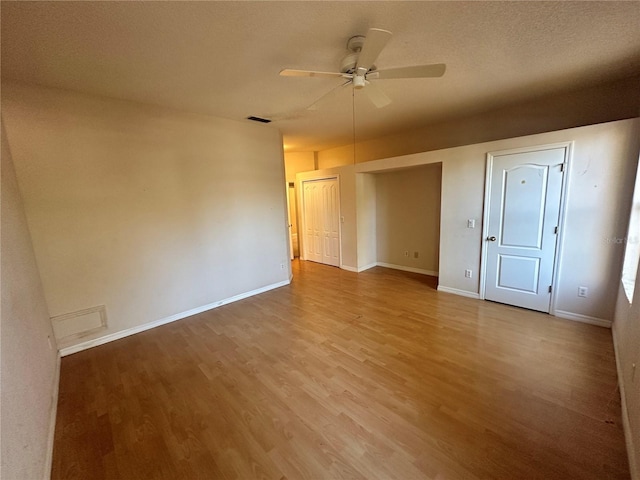 empty room featuring wood finished floors, a ceiling fan, visible vents, and baseboards