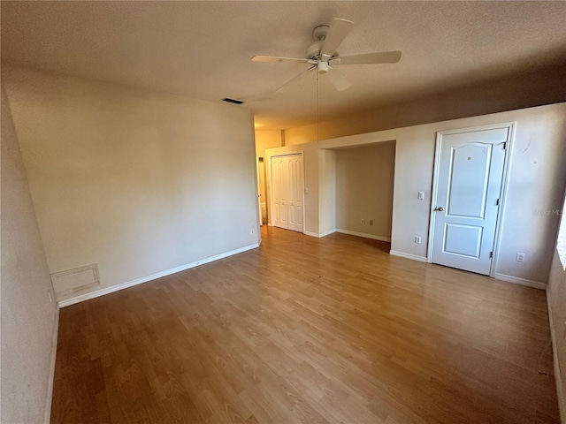 unfurnished room featuring visible vents, a textured ceiling, wood finished floors, baseboards, and ceiling fan