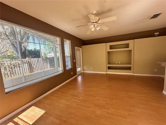 interior space with ceiling fan, light wood-style flooring, visible vents, and a textured ceiling