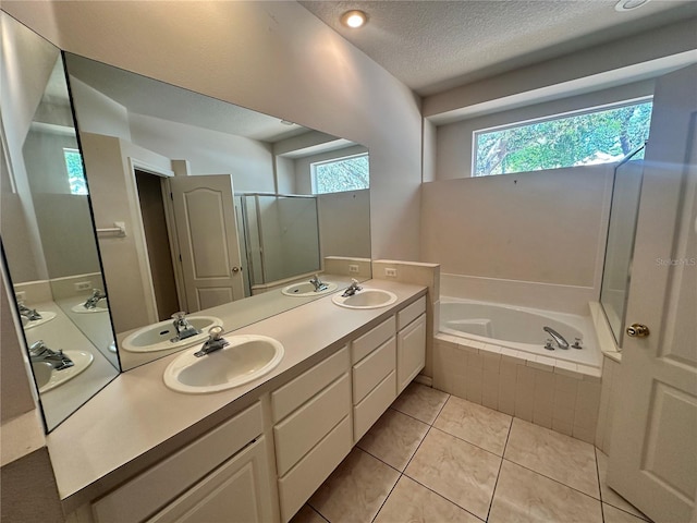 bathroom featuring double vanity, a stall shower, a sink, a textured ceiling, and a garden tub