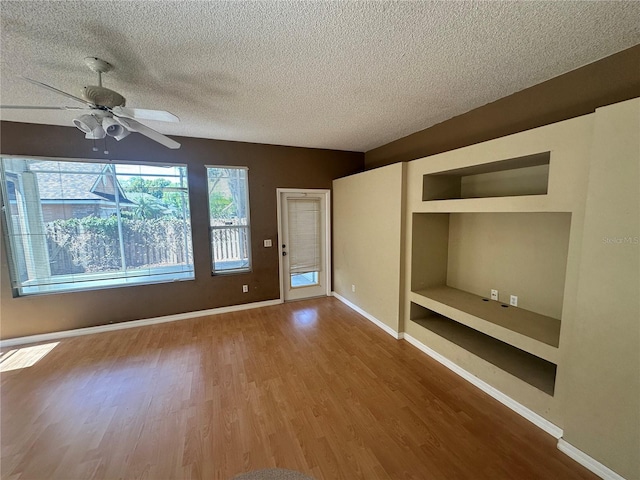 spare room with ceiling fan, baseboards, a textured ceiling, and wood finished floors