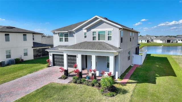 traditional home featuring cooling unit, decorative driveway, a front lawn, and stucco siding