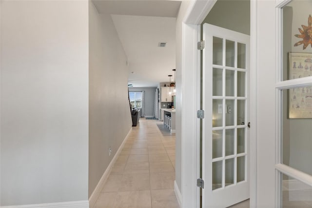 hallway featuring visible vents, baseboards, and light tile patterned flooring