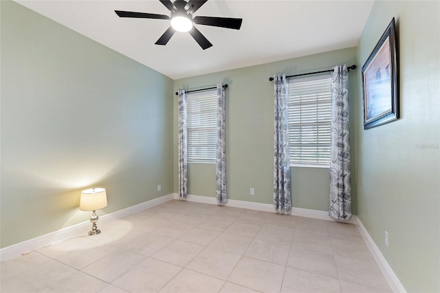 tiled spare room featuring a ceiling fan and baseboards